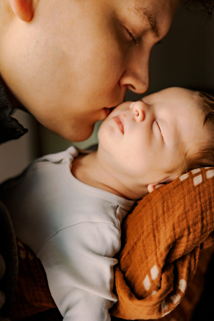 close-up shot of newborn being kissed by his dad