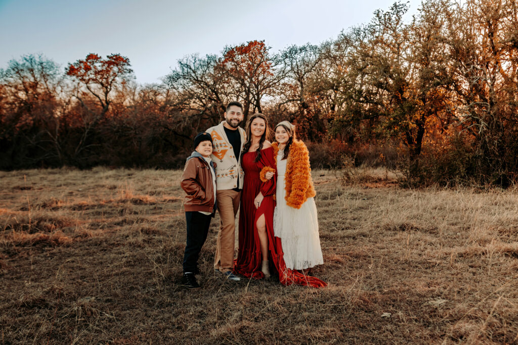 Family smiling into the camera in a sunset filled field
