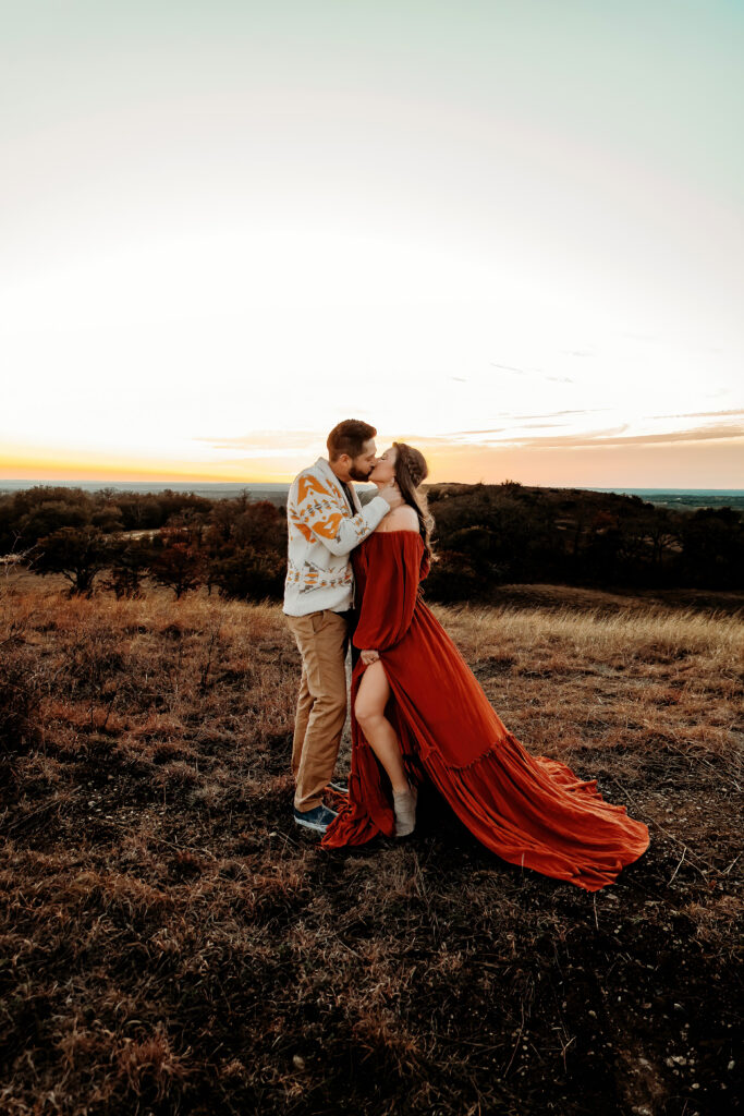 couple kissing on a sunset-lit hilltop
