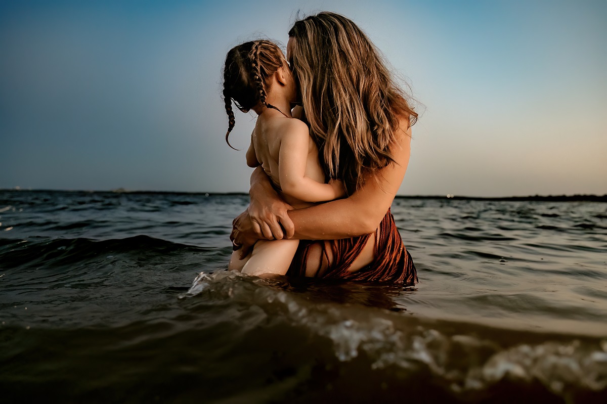 Mother and Daughter embracing in water at sunrise