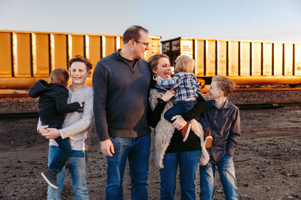family loving on each other in front of a train during a mini session