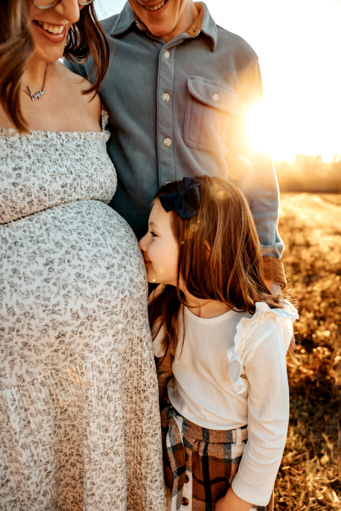 older sibling kissing baby bump during maternity photos with siblings