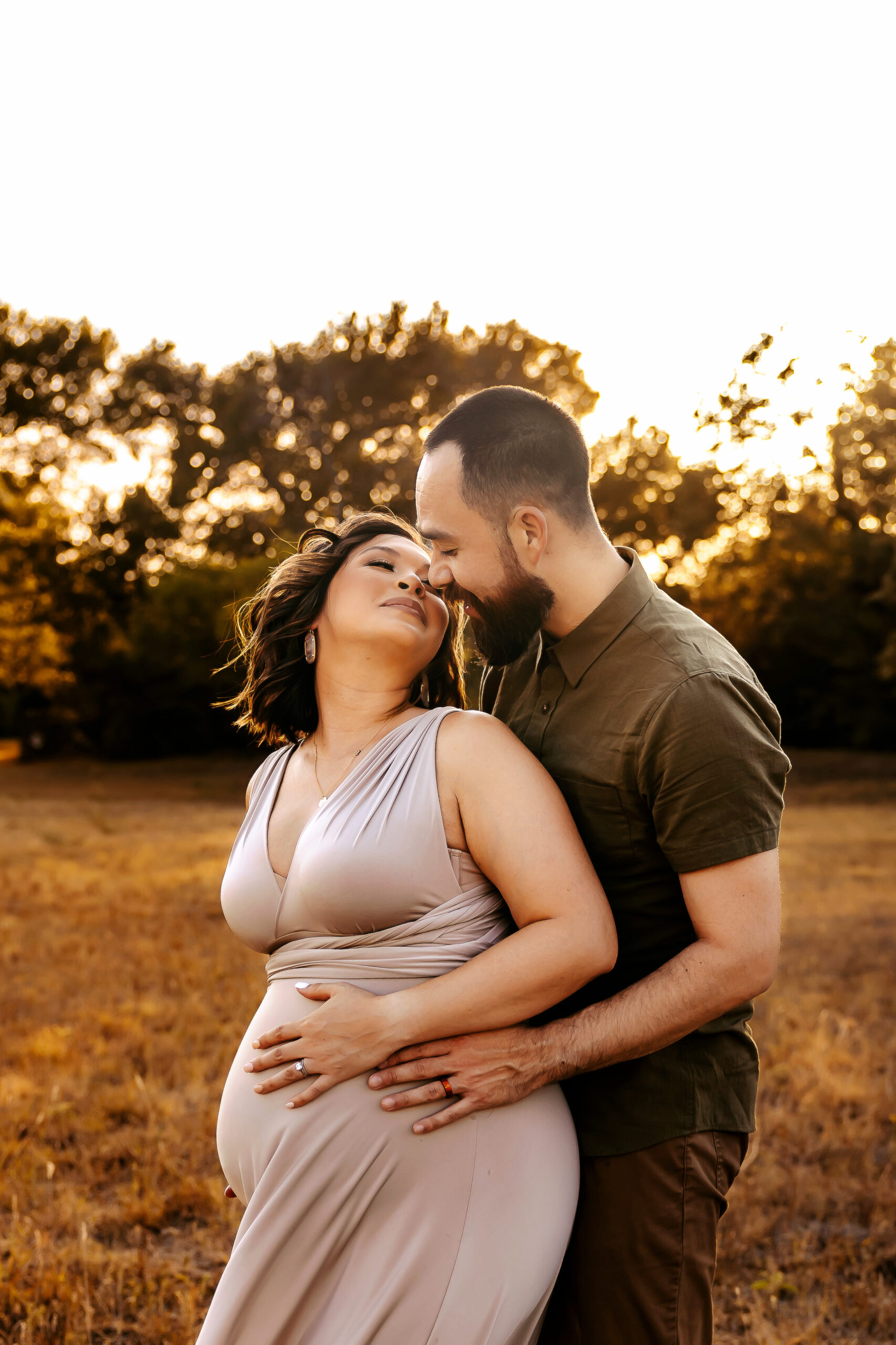 man and woman kissing while holding baby bump