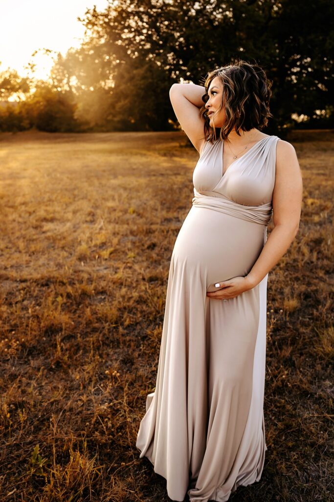 woman holding baby bump and looking into the sun