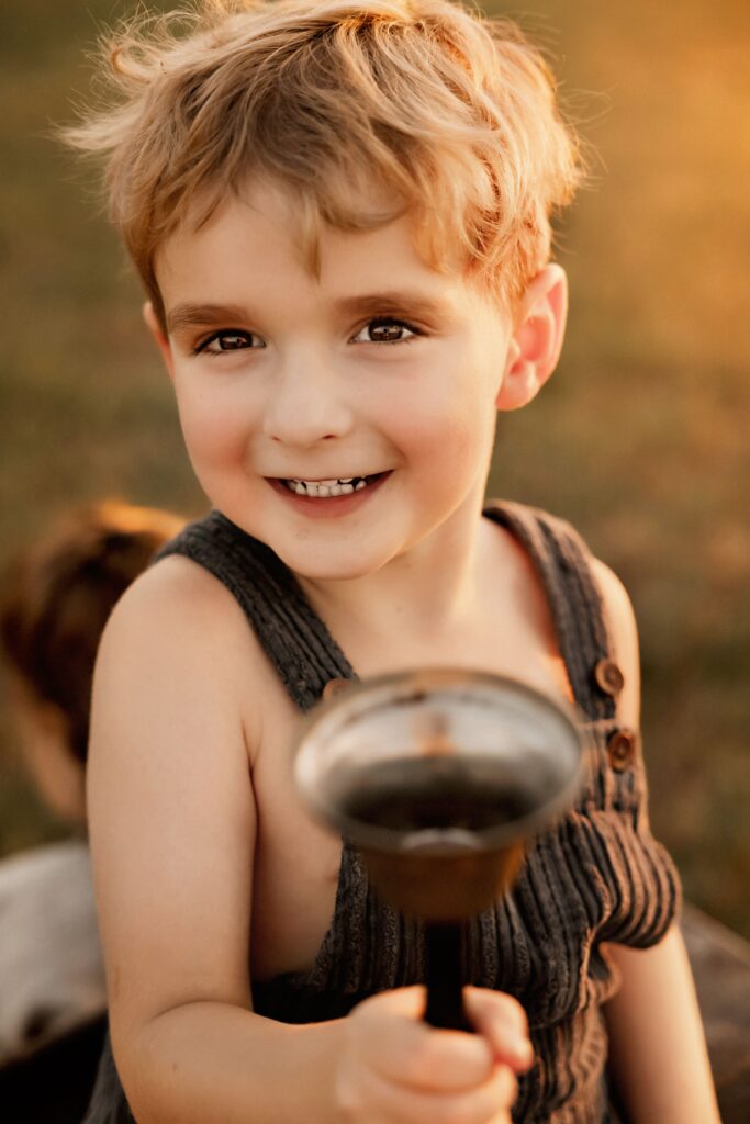 Child ringing a vintage school bell at sunset Fort Worth mini session