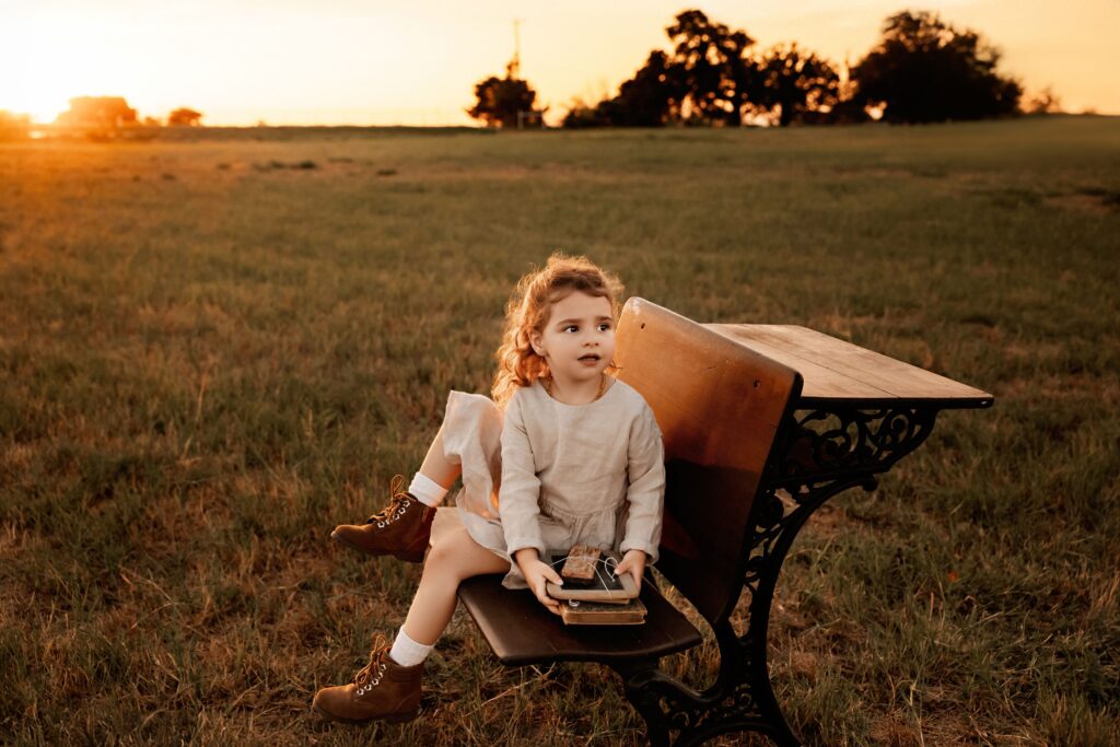 Child sitting at vintage school desk at sunset Fort Worth mini session