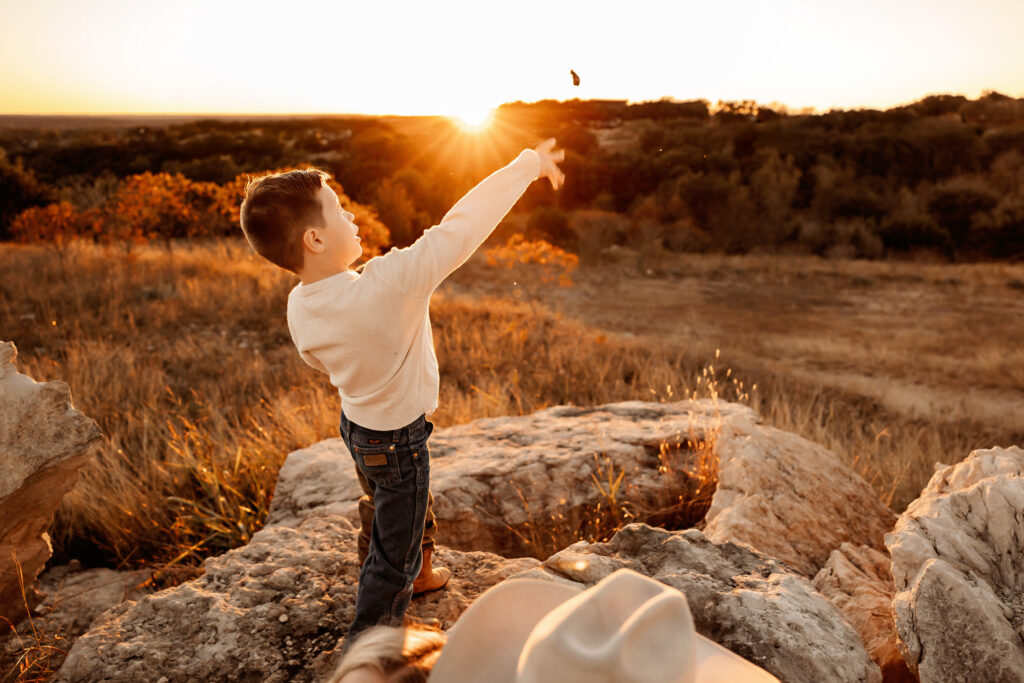 Brother throws a rock during a sunset photo session in Fort Worth Texas