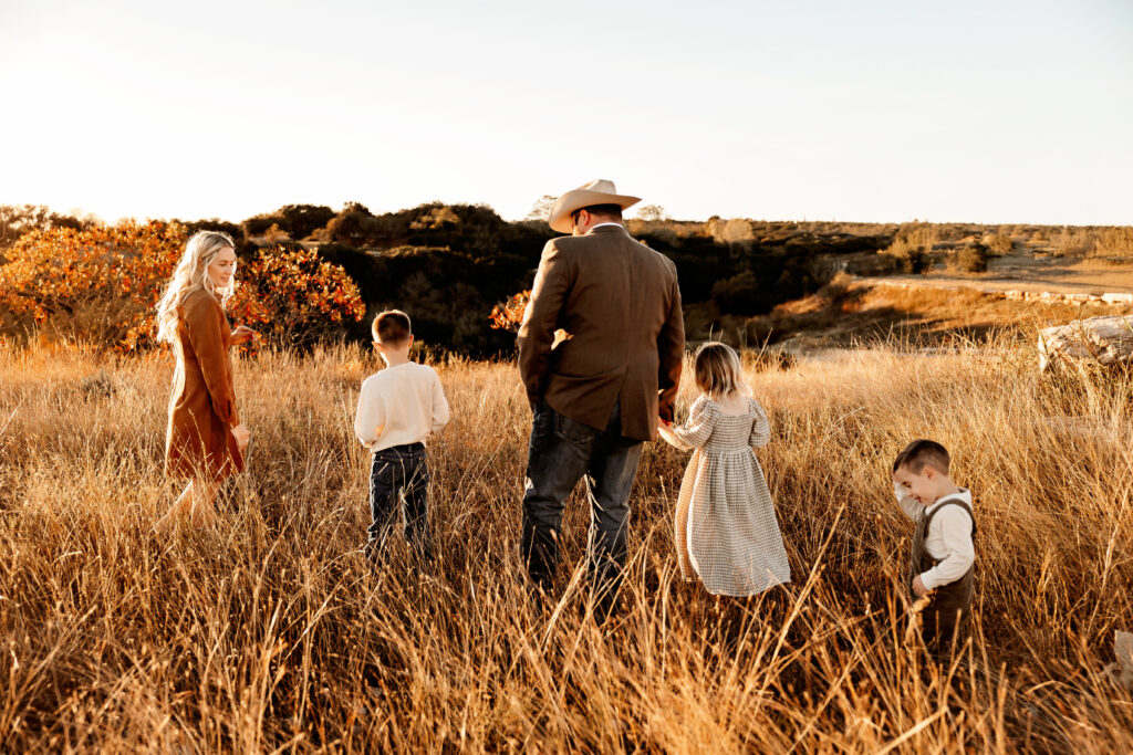 Family walking hand-in-hand through field during golden hour family session in Fort Worth