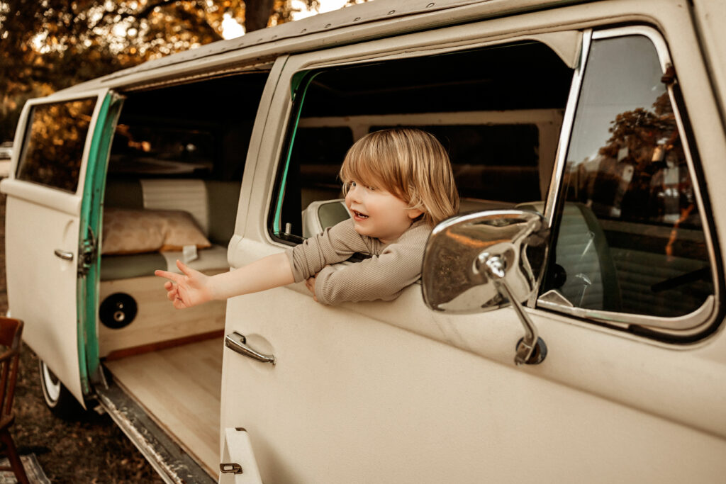 tiny wannabe hitchhiker thumbing for a ride in a VW Wagon during a family themed session