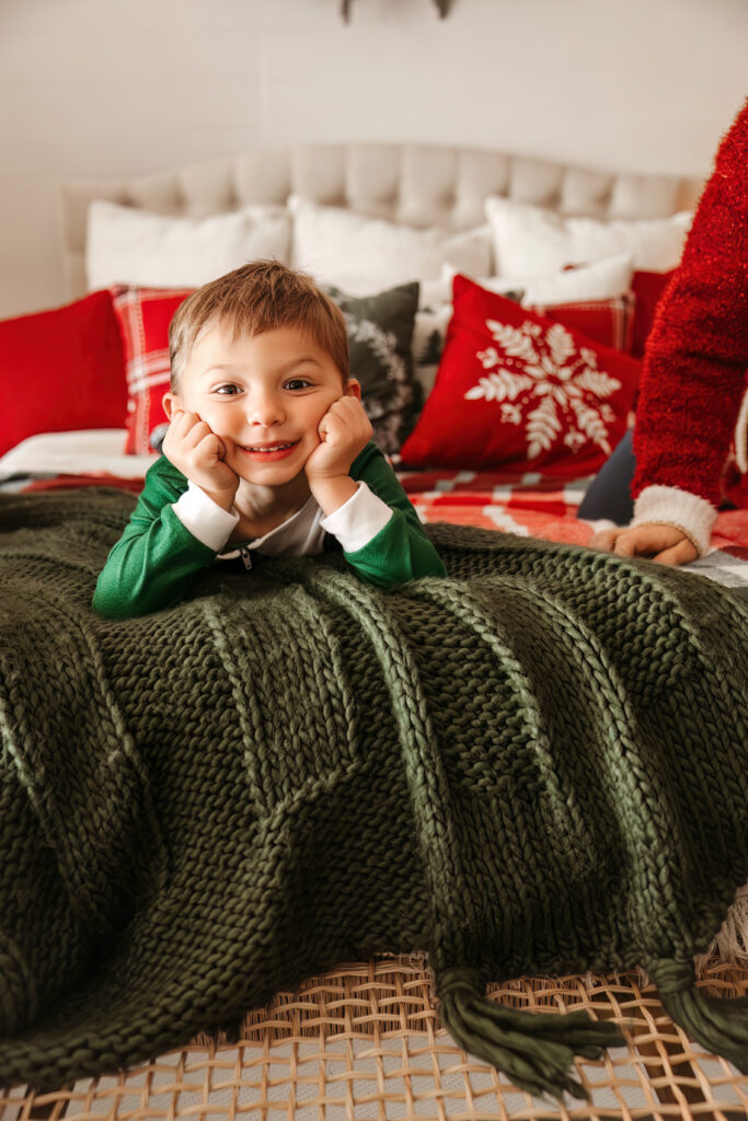 Child smiling on a bed during some Christmas Minis