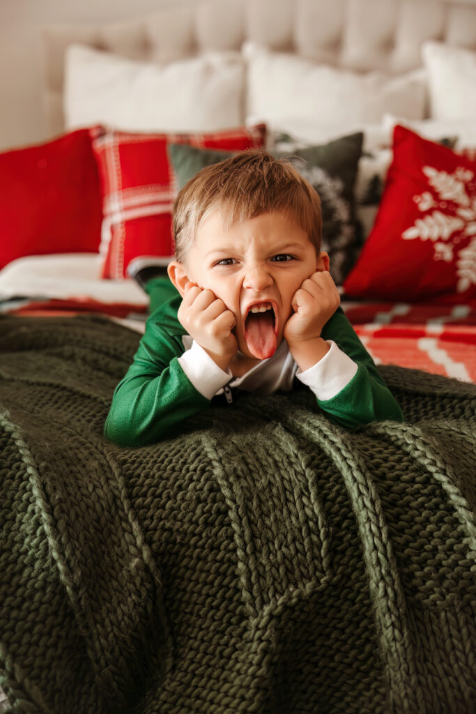 Child making silly faces on a bed during some Christmas Minis in Fort Worth