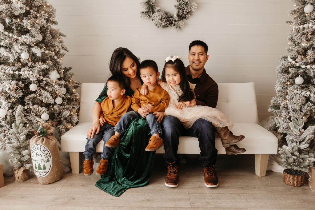 Parents cuddling with toddler in cozy studio decorated for the holidays