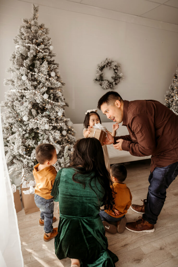 Child holding ornament and laughing during Fort Worth Christmas mini session