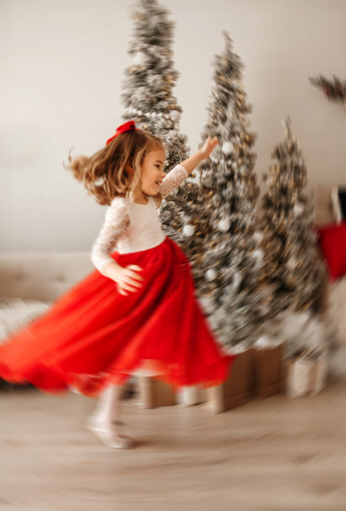 child dancing in front of a christmas tree
