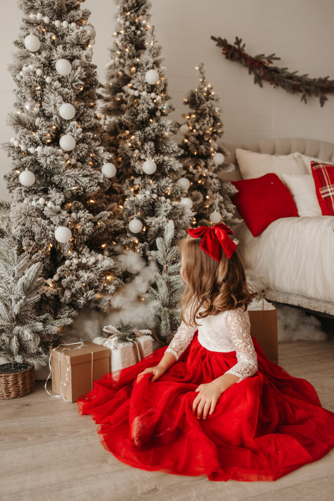 Child sitting next to a Christmas Tree and laughing during Fort Worth Christmas mini studio session